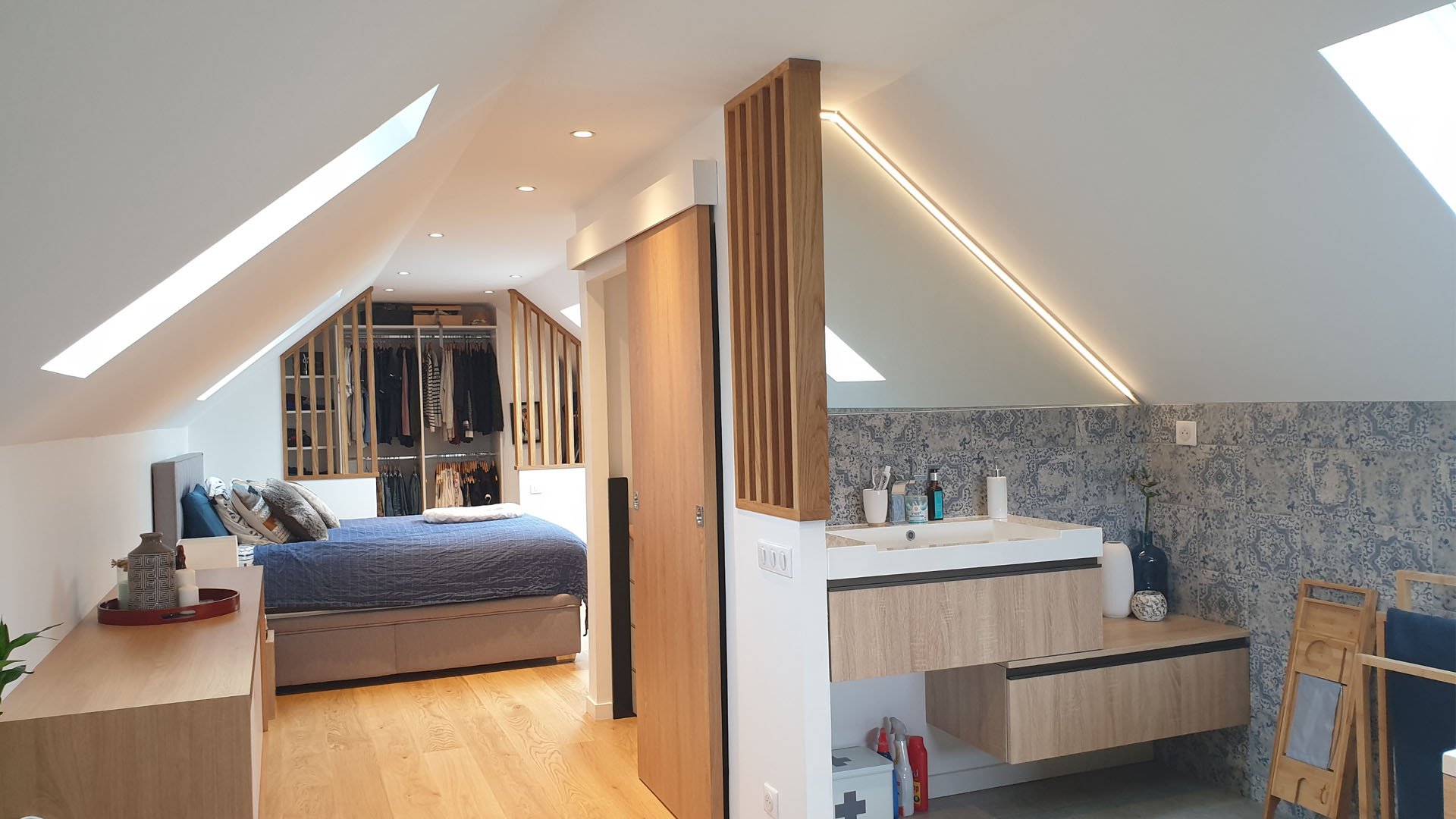 Combles transformés en suite parentale ouverte : bois naturel, pierre et salle de bain dans la chambre.