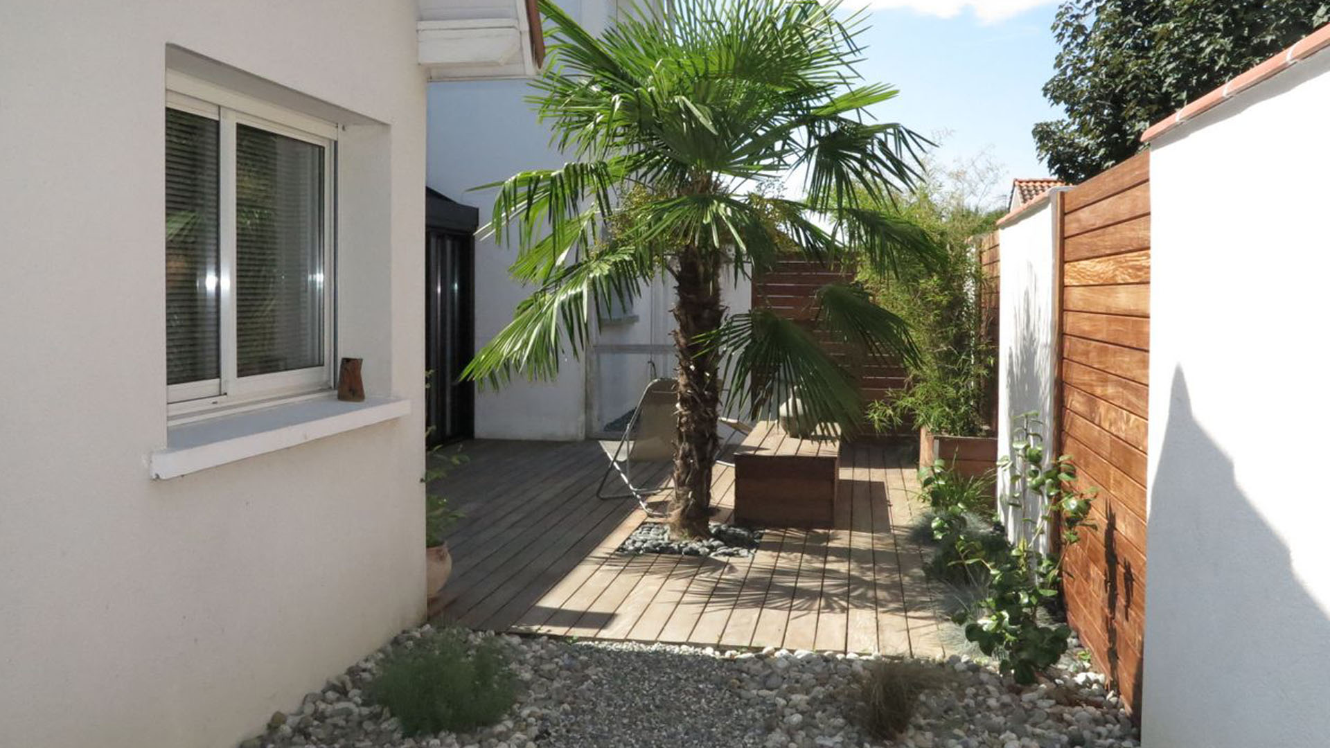 Aménagement complet d'un jardin à Lons : véranda sur mesure, terrasse bois et végétalisation structurée.